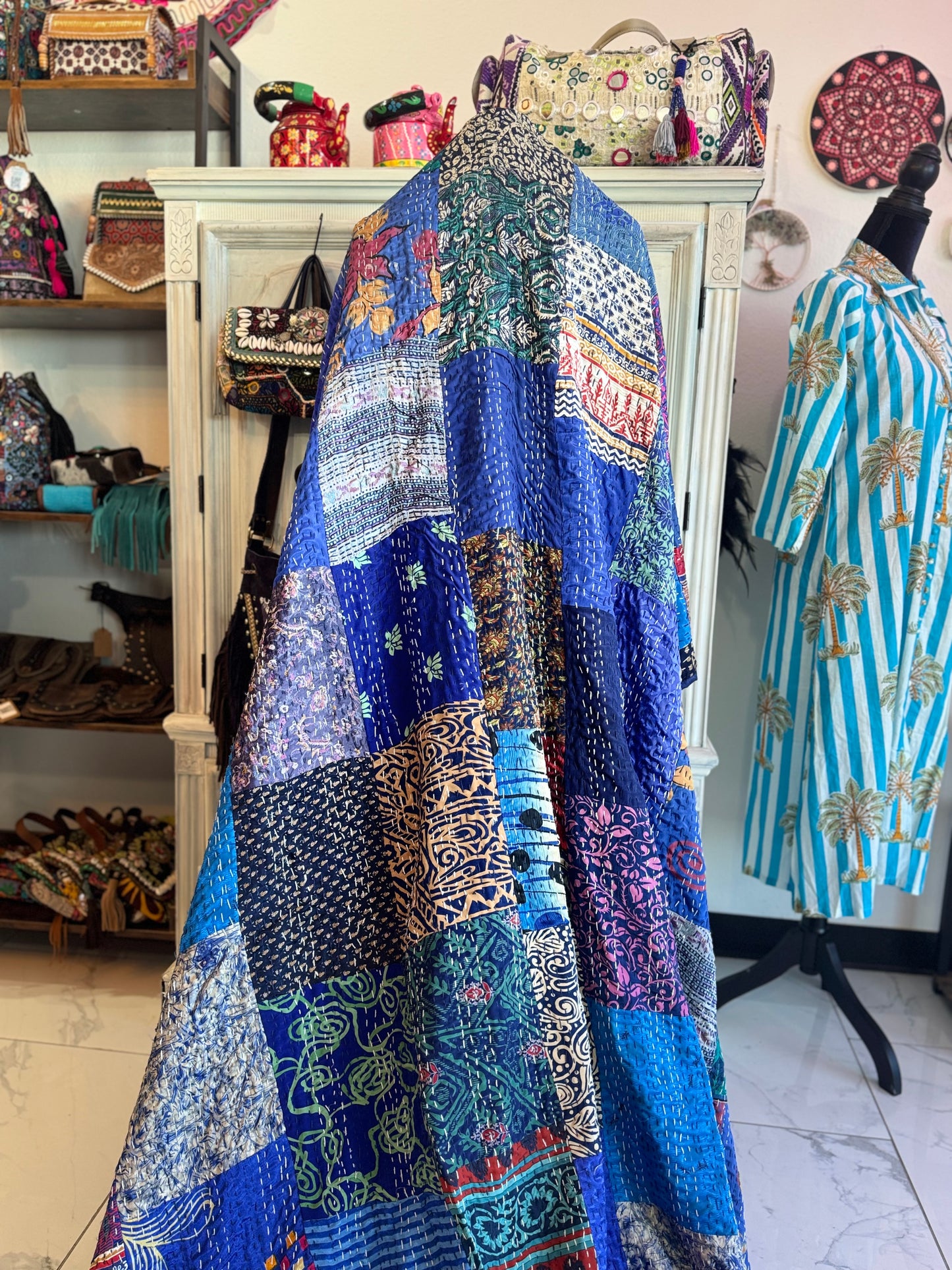Colorful patchwork dress hanging on a rack with a store interior in the background