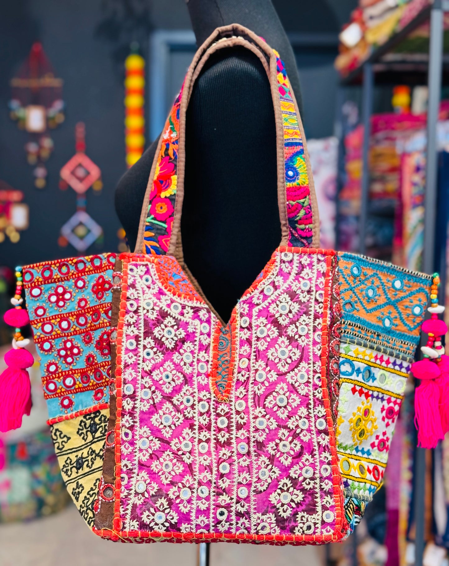 Vibrant white banjara tote bag backside with multi color embroidered patches, mirror work, cowrie shells, hot pink tassels.