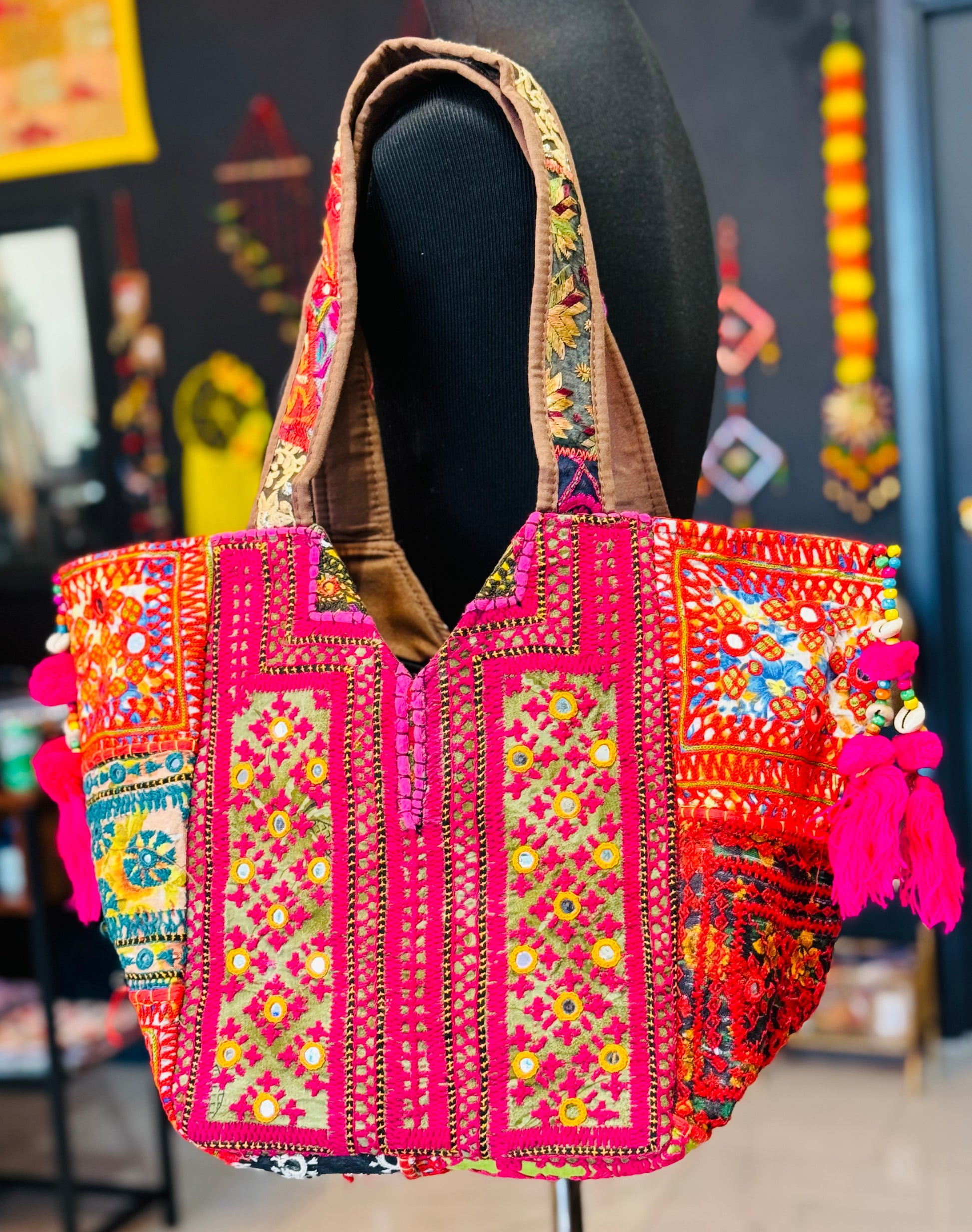 Vibrant Salmon banjara tote bag with multi color embroidered patches, mirror work, cowrie shells, hot pink tassels.