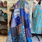 Colorful patchwork dress hanging on a rack with a store interior in the background