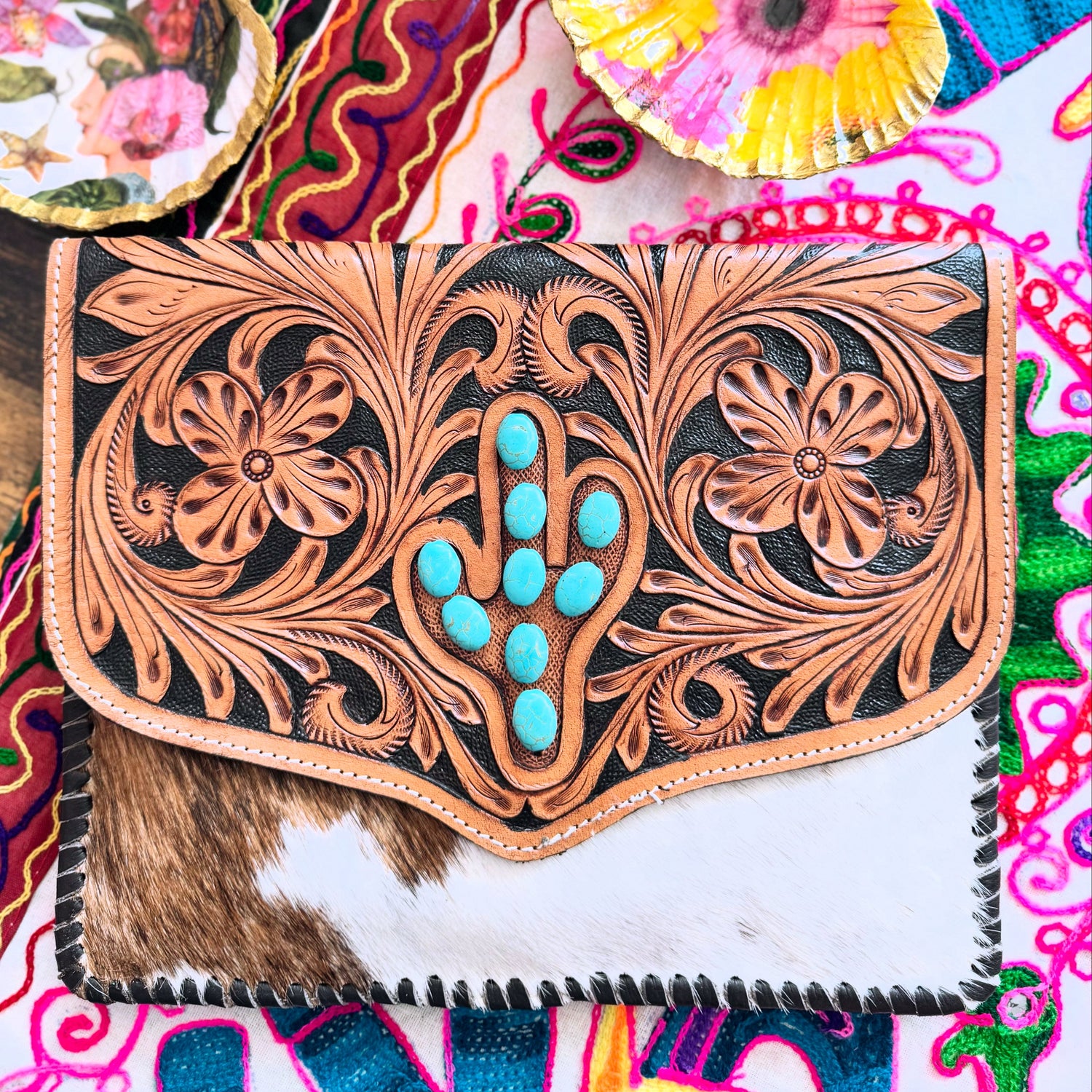 A handcrafted shoulder bag with a floral design and turquoise stones, made from genuine cowhide and hand-tooled leather, featuring a cactus motif.