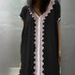 Black dress with intricate white and pink lace work on the front of the kaftan