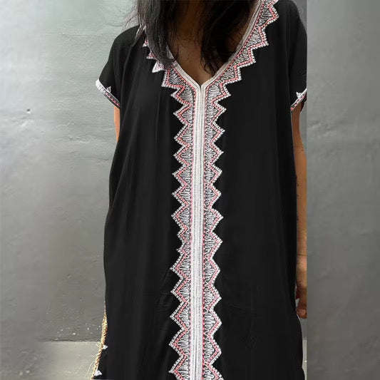 Black dress with intricate white and pink lace work on the front of the kaftan
