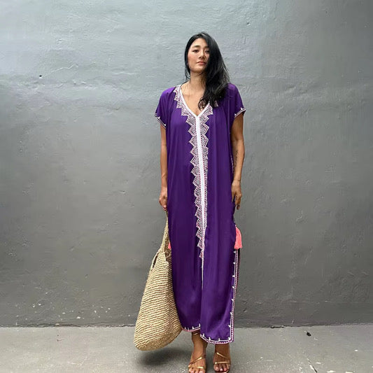 A purple kaftan dress with white lace trim 