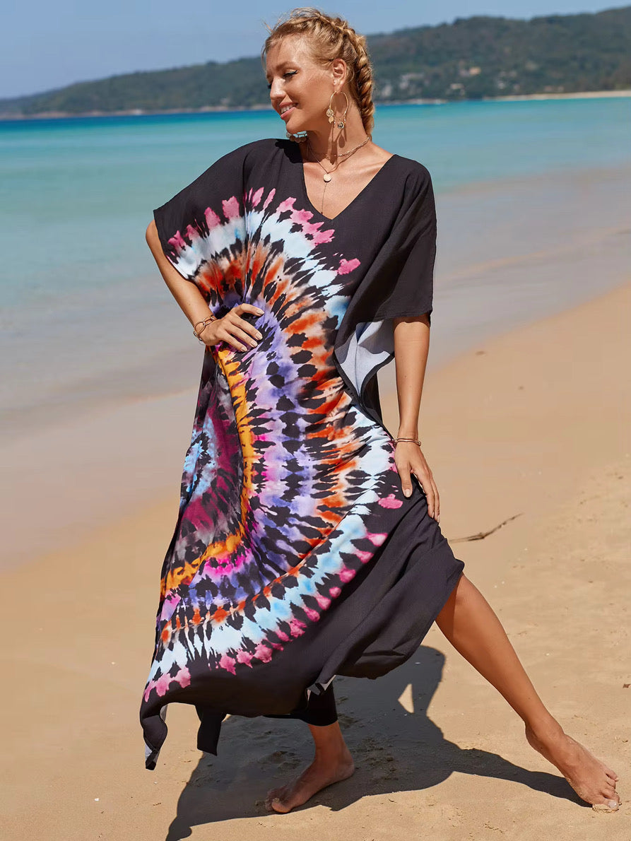 Woman wearing a black dress with a colorful tie-dye pattern on a beach.